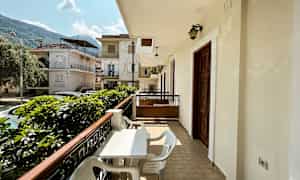 Altan med bord og stole og udsigt mod et boligområde med huse. (AI-genereret tekst)