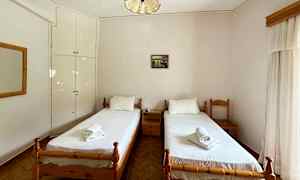 Billede af et hotelværelse med to enkeltsenge med hvidt sengetøj, placeret mod en lys væg med et lille vægskab. (AI-genereret tekst)