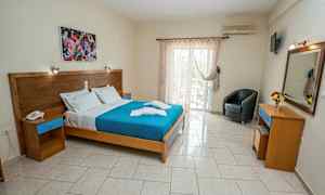 Et hotelværelse med en dobbeltseng, maleri over sengen, og glasdøre der fører til en balkon. (AI-genereret tekst)