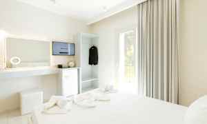 Et hotelværelse med en opredt seng, TV, køleskab og garderobe. (AI-genereret tekst)