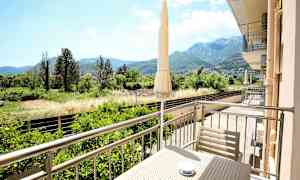 En altan med udsigt over en frodig dal og bjerge i baggrunden. (AI-genereret tekst)