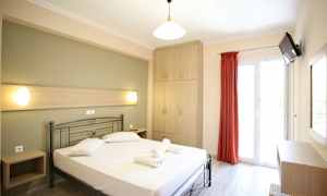 Et lyst hotelværelse med en seng, et skab og en altandør. (AI-genereret tekst)