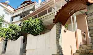 Et flerfamiliehus med flere altaner, en buet port med skiltet 'Giovanni' og grønne områder ved indgangen. (AI-genereret tekst)