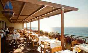 Restaurantterrasse med dækkede borde og havudsigt. (AI-genereret tekst)