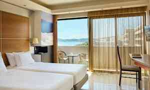 Værelse med to enkeltsenge, en altan med havudsigt og siddepladser. (AI-genereret tekst)