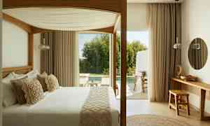 Et soveværelse med en himmelseng, udsigt mod en terrasse og poolområde. (AI-genereret tekst)