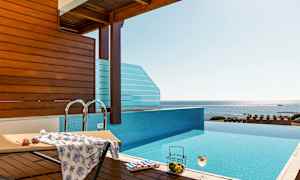 En infinity-pool med udsigt over havet, en liggestol og en drink. (AI-genereret tekst)