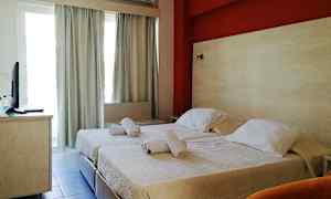 Et hotelværelse med to enkeltsenge og en rød væg bag dem. (AI-genereret tekst)