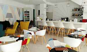 Indenfor visning af en stilfuld café med farverige stole, et barområde og dekorative elementer. (AI-genereret tekst)