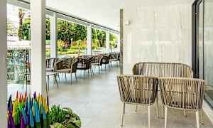 Udendørsmøbler med rottingstole og borde på en terrasse, med planter og udsigt til gaden. (AI-genereret tekst)