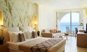 Hotelværelse med havudsigt og moderne indretning, herunder seng, sofa og balkon. (AI-genereret tekst)