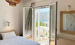 Værelse med seng, åben altandør og udsigt over et bjergrigt landskab. (AI-genereret tekst)