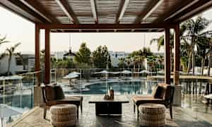 En terrasse med siddepladser, der vender mod en udendørs pool og palmer. (AI-genereret tekst)