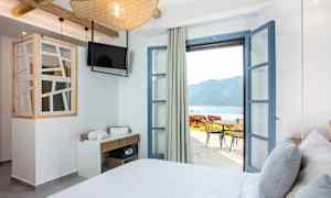 Hotelværelse med åbne døre til terrasse og havudsigt. (AI-genereret tekst)