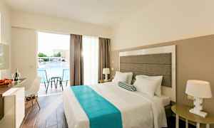 Et hotelværelse med en dobbeltseng, natbord, en stol og et skrivebord. Vindue med udsigt over en pool. (AI-genereret tekst)