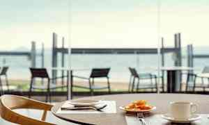 En tallerken med frugt og en kop på et bord, med udsigt over stranden. (AI-genereret tekst)