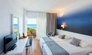 Hotelværelse med to senge og balkon med udsigt over havet. (AI-genereret tekst)