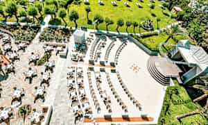 Luftfoto af udendørs siddeområde og grønt område med træer og parasoller. (AI-genereret tekst)