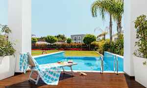 Udendørs pool omgivet af grønne områder og liggestole. (AI-genereret tekst)