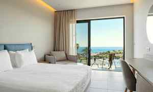 Hotelværelse med seng, sofa og udsigt over havet. (AI-genereret tekst)