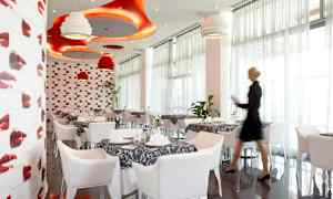 En restaurant med moderne indretning i rødt og hvidt, med dækkede borde og dekorative loftslamper. (AI-genereret tekst)