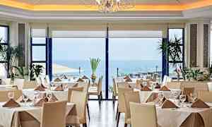 Restaurant med dækkede borde, store vinduer og havudsigt. (AI-genereret tekst)