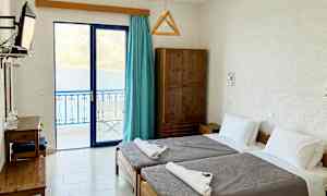 Et hotelværelse med to enkeltsenge og udsigt over havet gennem glasdøre. (AI-genereret tekst)