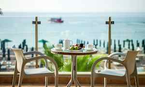 To stole ved et bord med frugt og drikke med udsigt over havet. (AI-genereret tekst)