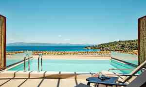 En moderne udendørs swimmingpool med udsigt over havet og et frodigt landskab. (AI-genereret tekst)