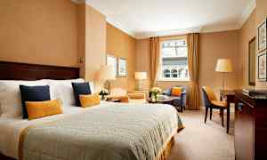 Et elegant hotelværelse med en bred seng, siddeområde og vindue med udsigt. (AI-genereret tekst)