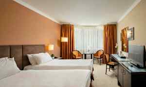 Hotelværelse med to enkeltsenge, et bord, to stole og et fjernsyn. (AI-genereret tekst)