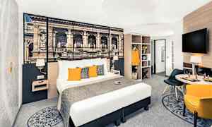 Hotelværelse med dobbeltseng, vægdekoration, siddeområde og garderobe. (AI-genereret tekst)