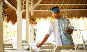 En tjener med en serveringsbakke og glas gør et bord klar på en restaurant. (AI-genereret tekst)