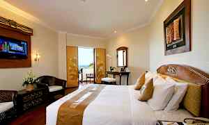 Et hotelværelse med en dobbeltseng, skrivebord, siddeområde og en altan med udsigt. (AI-genereret tekst)