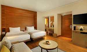 Et moderne hotelværelse med to separate senge, et skrivebord med spejl, en sofa og et lille bord. (AI-genereret tekst)