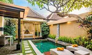 En terrasse med en lille pool omgivet af grønne planter og et hus i baggrunden. (AI-genereret tekst)