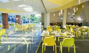 Billede af en moderne restaurant med gule stole og glasvægge. (AI-genereret tekst)