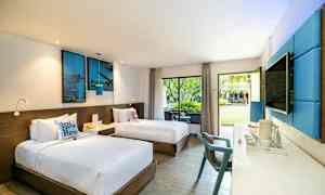 Et hotelværelse med to enkeltsenge, moderne indretning med blå detaljer, og store vinduer som vender ud mod en have. (AI-genereret tekst)