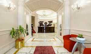 En elegant hotellobby med marmorgulv, en reception med mørkt træpanel og en elegant lysekrone. (AI-genereret tekst)