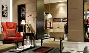 En elegant møbleret stue med røde og beige stole, blomster og bogreoler. (AI-genereret tekst)