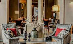 To lænestole med puder foran et bord med dekorationsgenstande, i en elegant indrettet atmosfære. (AI-genereret tekst)