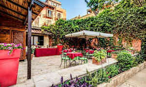 Udendørsområde med borde og stole samt beplantning. (AI-genereret tekst)