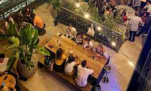 En restaurant med mennesker, der sidder ved borde og spiser i en afslappet atmosfære. (AI-genereret tekst)