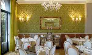 En restaurant med grønne vægge, stilfulde stole og borde med duge. (AI-genereret tekst)