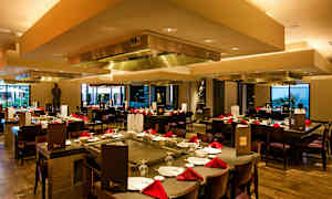 En restaurant med borde dækket med røde servietter og stole rundt om. (AI-genereret tekst)