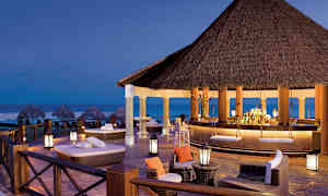 Afslappet lounge og bar med stråtag, ved stranden ved skumring. (AI-genereret tekst)