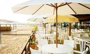 En strandbar med parasoller og hvide borde og stole. (AI-genereret tekst)