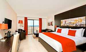 Et hotelværelse med seng, siddeområde og altandør. (AI-genereret tekst)