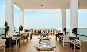 Restaurant med udendørs borde og havudsigt. (AI-genereret tekst)