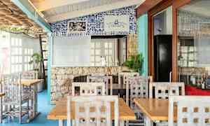 Restaurant med træborde og stole samt dekoreret væg med blå kakler. (AI-genereret tekst)